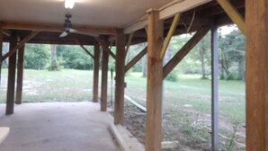A covered outdoor area with wooden beams and a concrete floor, likely a patio or deck area. - Wendell’s Place on Red Creek - Uncle Ralph’s Cabin Rentals - PRIVATE BEACH (Perkinston)