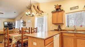 A spacious kitchen with wooden cabinets, a central island, and a dining area with chairs.
