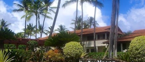 A resort with a stone sign reading "NiHi Kai Villas Resort" surrounded by lush greenery and tall palm trees.