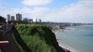 A coastal cityscape with a prominent green hill, a beach, and a city skyline in the background. - Right in the middle of the action Safe comfort  (Miraflores)