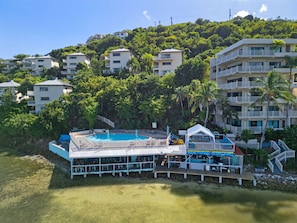 A resort with a pool, multiple buildings, and a hillside backdrop.