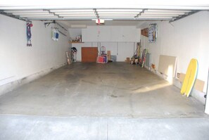 Eine Garage mit Betonboden, einer roten Werkzeugkiste und einem gelben Surfbrett, das an der Wand lehnt.