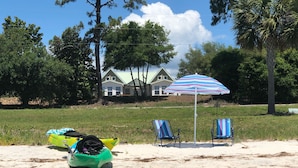 Une plage avec des kayaks, un parasol rayé et des chaises de plage.