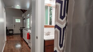 A kitchen with wooden flooring, white cabinets, and a window with a view of trees. - Newly built deluxe cabins, in a private redwood setting near the Smith River (Hiouchi)