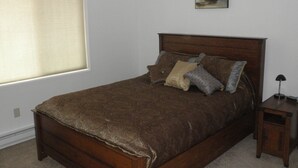 A bedroom with a wooden bed, a nightstand, a window with blinds, and a painting on the wall. - You have to get out-of-town to see the wildlife (Homer)