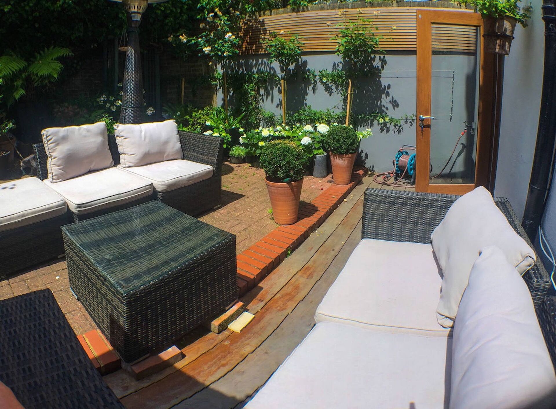 A patio with wicker furniture, potted plants, and a wooden door.
