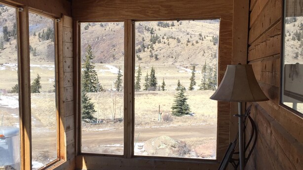 Ein Zimmer mit großen Fenstern, Holzwänden und einem blauen Teppich.