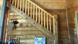 Ein Holzinnenraum mit Treppe, Holzbalken und einem sichtbaren Kamin.