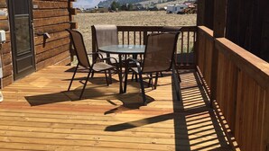 Eine Holzterrasse mit Tisch und Stühlen, einer Tür und Blick auf eine Berglandschaft.