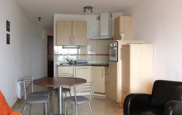 Une cuisine de taille réduite comprenant une table et des chaises, un réfrigérateur et une cuisinière.