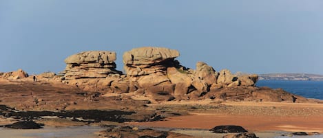 Un paysage côtier caractérisé par d’imposantes formations rocheuses et une plage de sable.