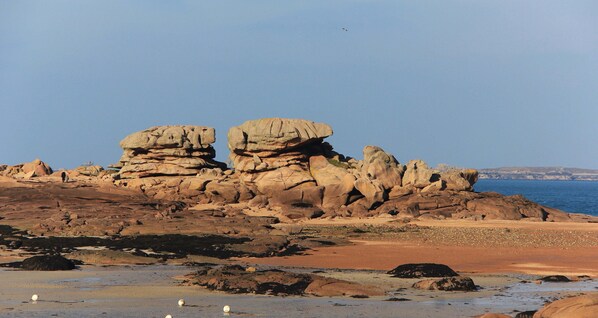 A coastal landscape with prominent rock formations and a sandy beach. - Apartment with terrace facing the 7 islands, up to 4 people (Perros-Guirec)