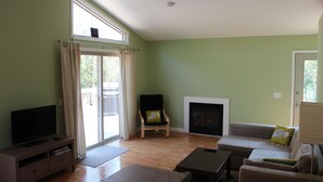 A living room with a television, a sofa, a chair, and a fireplace. - Cedar Cottage - Kelleys Island (Lake Erie) Vacation Retreat (Kelleys Island)