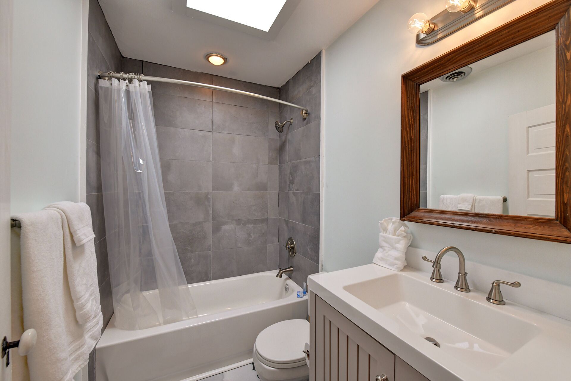 A modern bathroom with a bathtub, shower, toilet, and vanity.