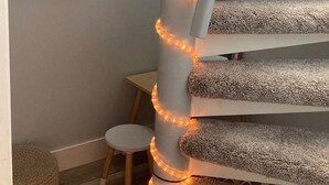 Een wenteltrap met een gestructureerd tapijt en warme LED-verlichting.