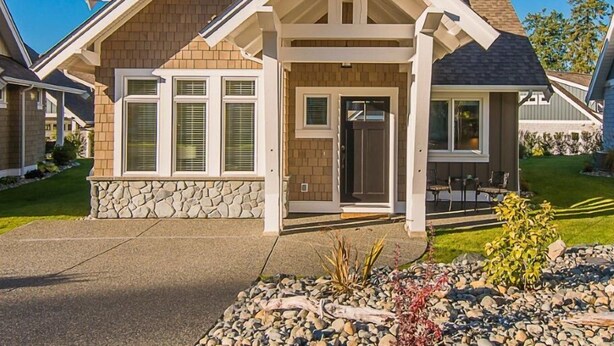 Une maison à deux étages, avec des fondations en pierre, un porche à l’avant et une pelouse bien entretenue.
