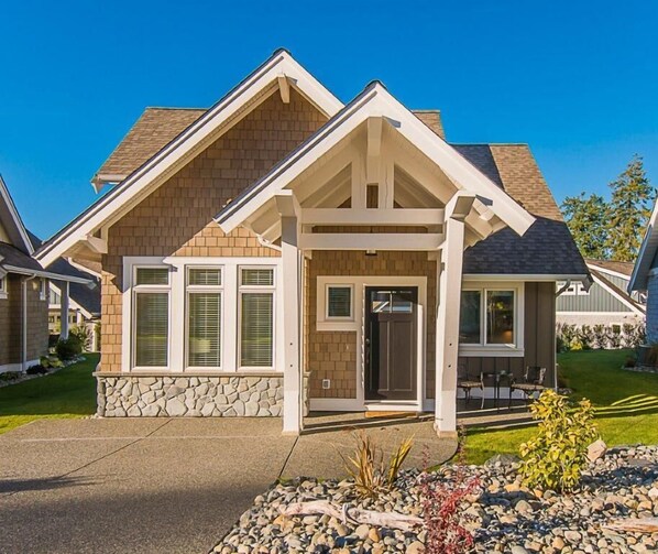 Une maison à deux étages, avec des fondations en pierre, un porche à l’avant et une pelouse bien entretenue.