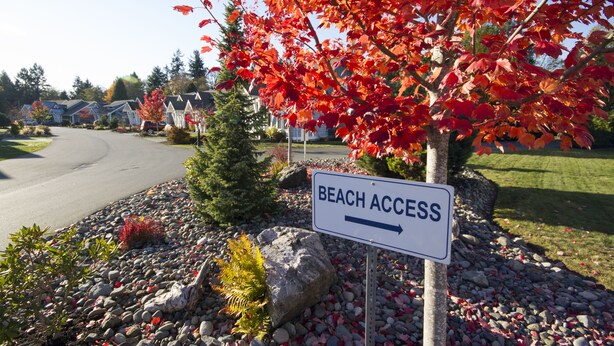 Eine Wohnstraße mit einem Schild, das 'Beach Access' zeigt und den Weg zum Strand weist.