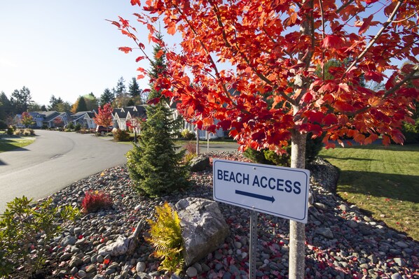Calle residencial con un cartel que indica 'Beach Access' y señala la dirección a la playa.