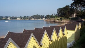 Uitzicht op een waterkant met gele gebouwen en een zandstrand.