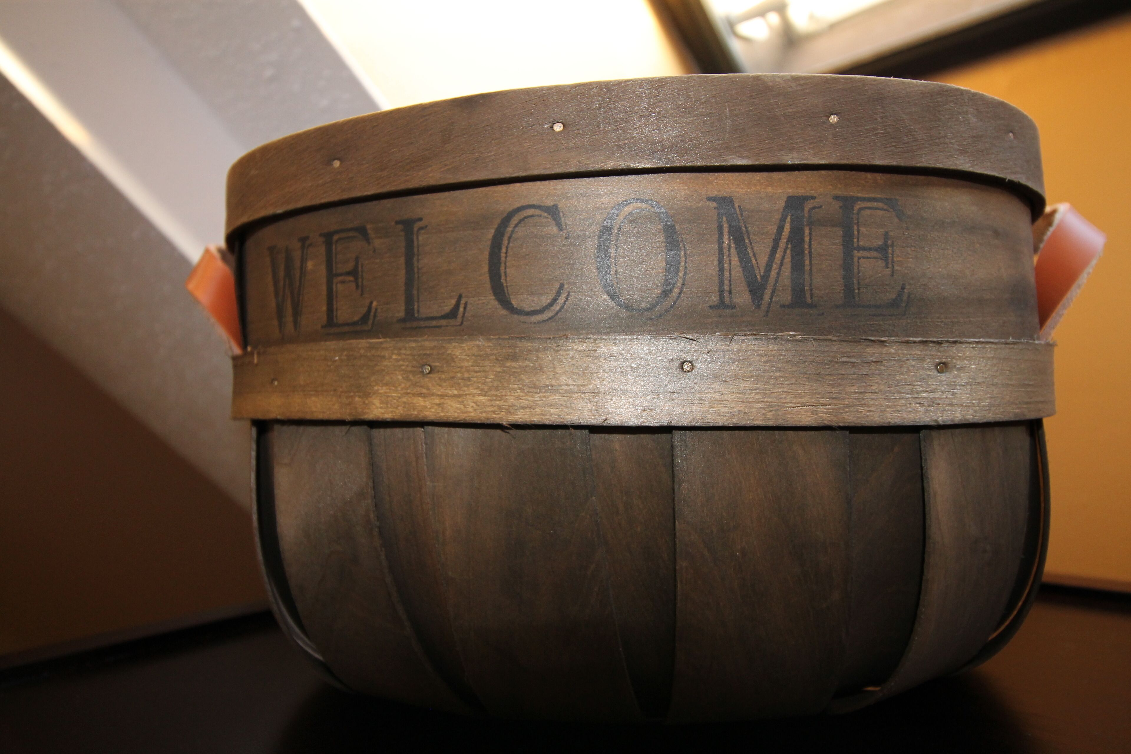 Ein hölzernes Willkommensschild mit der eingravierten Aufschrift 'WELCOME'.
