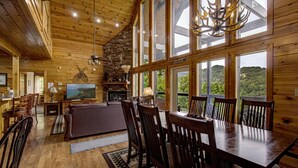 Une cabane en bois spacieuse, dotée d’un grand espace repas, d’une cheminée et d’un téléviseur.