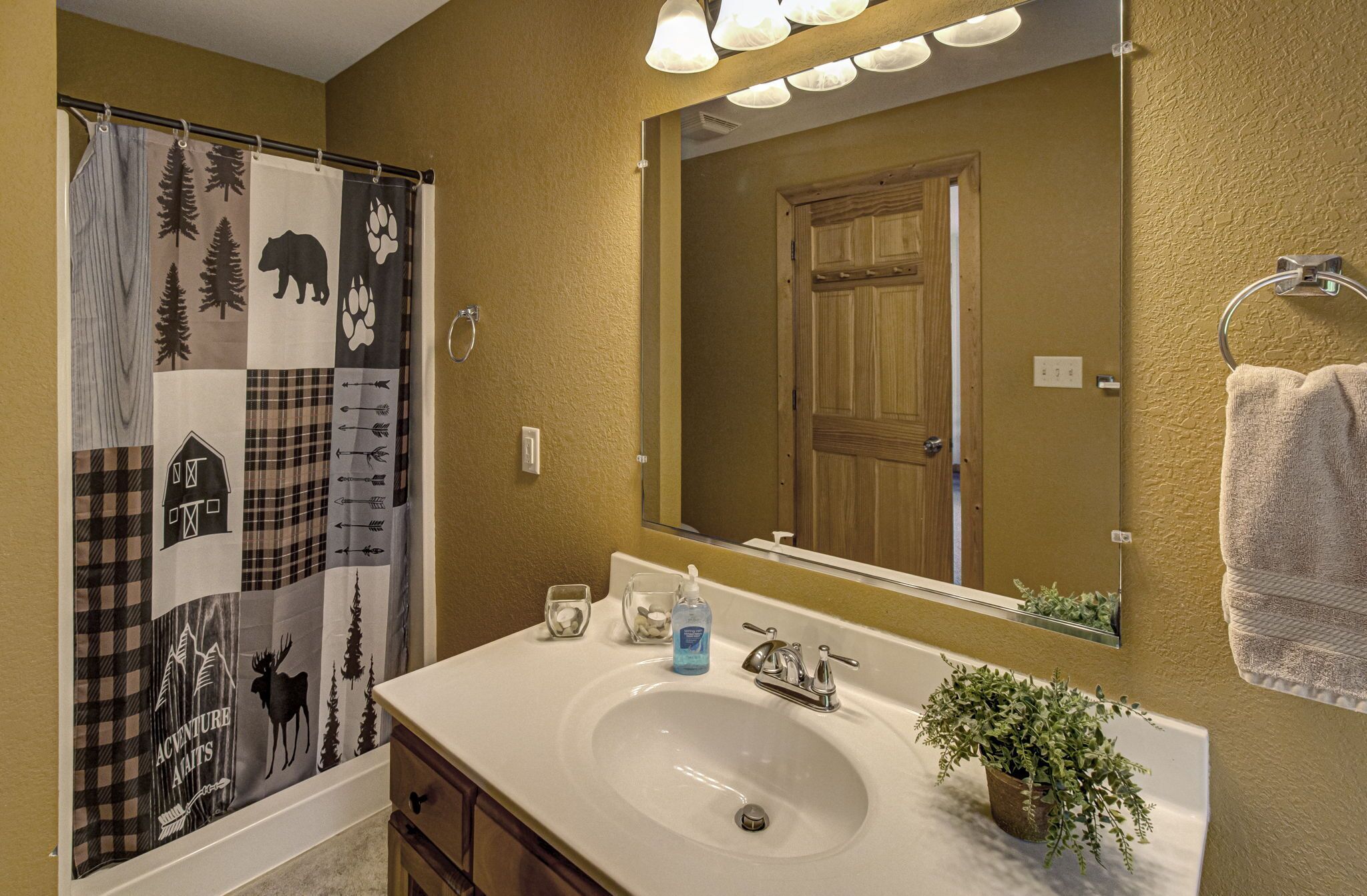 A bathroom with a white sink, a mirror, a towel rack, and a shower curtain with animal prints.