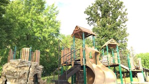Un parque infantil con tobogán, estructuras para escalar y una pared de escalada.