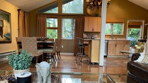 A spacious living area with a dining table, chairs, a glass coffee table, and a sofa. - Beautiful Lake Whatcom/Sudden Valley House Rental steps from the water (Bellingham)