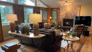 A cozy living room with a fireplace, leather sofa, and a stone accent wall. - Beautiful Lake Whatcom/Sudden Valley House Rental steps from the water (Bellingham)