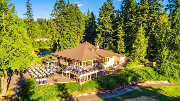 An aerial view of a lodge with a large parking area, a covered deck, and a building surrounded by dense forest. - Beautiful Lake Whatcom/Sudden Valley House Rental steps from the water (Bellingham)