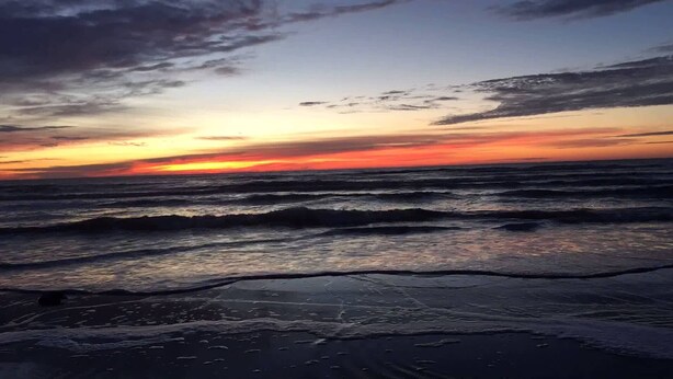 Una playa con olas y un atardecer.