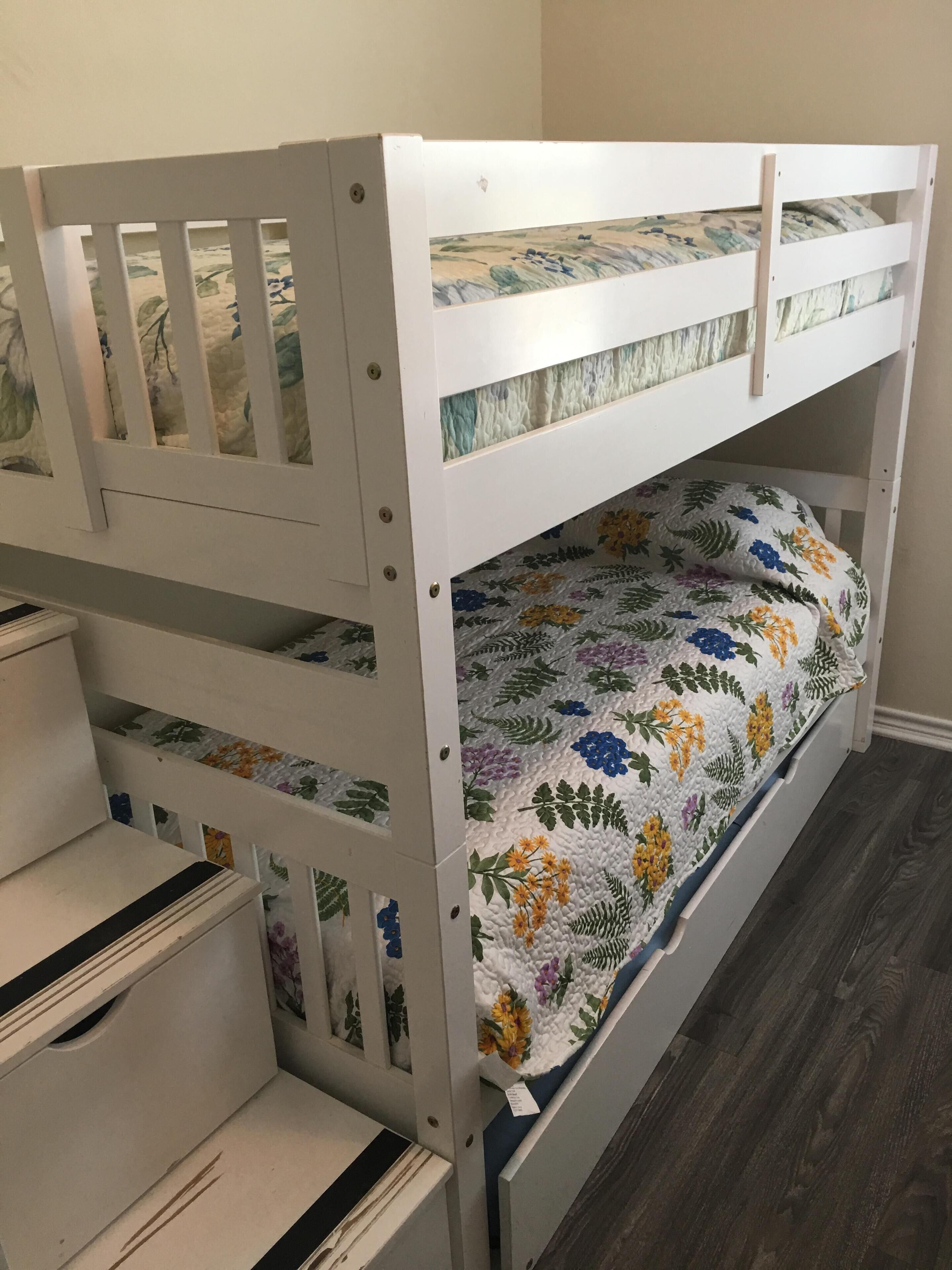 A bunk bed with a floral-patterned mattress and a white metal frame.