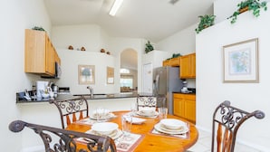 A dining area with a wooden table set for four, surrounded by metal chairs.