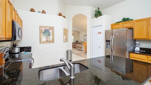 A kitchen with granite countertops, stainless steel appliances, wooden cabinets, and a framed picture on the wall.