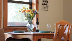 Une table à manger ornée d’un vase de fleurs, d’une bouteille de vin et d’un verre.