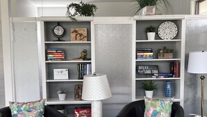 Ein Wohnzimmer mit zwei schwarzen Ledersesseln, einer weißen Lampe und einem Bücherregal voller Bücher und Dekoration.