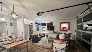 Ein modernes Wohnzimmer mit Essbereich, Holzboden und einem großen Fenster.