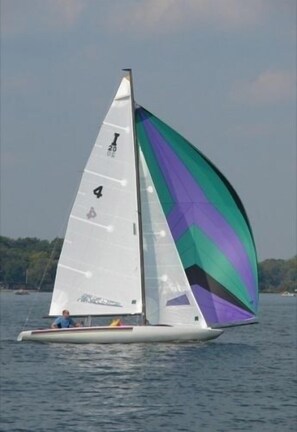 A sailboat with a white hull and a colorful sail, sailing on a body of water.