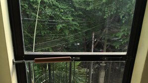 A balcony with a view of a lush green garden and a tiled floor. - Cozy private apartment - Walk to the center (Dumaguete City)
