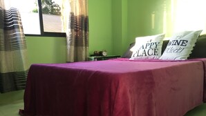 A bed with a purple bedspread, two pillows with text, a clock, and a window with curtains. - Cozy private apartment - Walk to the center (Dumaguete City)