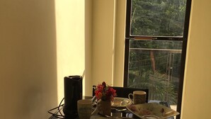 A dining table set with plates, a vase of flowers, and a mug. - Cozy private apartment - Walk to the center (Dumaguete City)