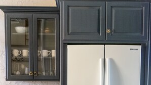 A kitchen with dark cabinetry, a white refrigerator, and a wooden tray on the counter. - Family-Friendly 1830s Cville Row House Near Downtown Mall, UVA, & Monticello (Charlottesville)