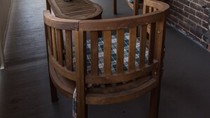 A wooden table and chairs on a covered porch with a brick wall and windows. - Family-Friendly 1830s Cville Row House Near Downtown Mall, UVA, & Monticello (Charlottesville)