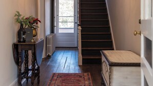A hallway with a chandelier, a staircase, a radiator, and a rug. - Family-Friendly 1830s Cville Row House Near Downtown Mall, UVA, & Monticello (Charlottesville)