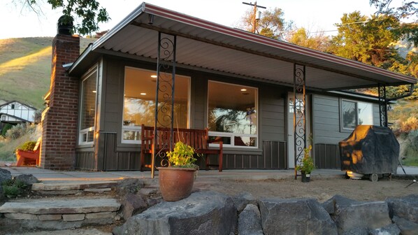 Una casa moderna con porche cubierto, ventanas grandes y una chimenea de ladrillo.