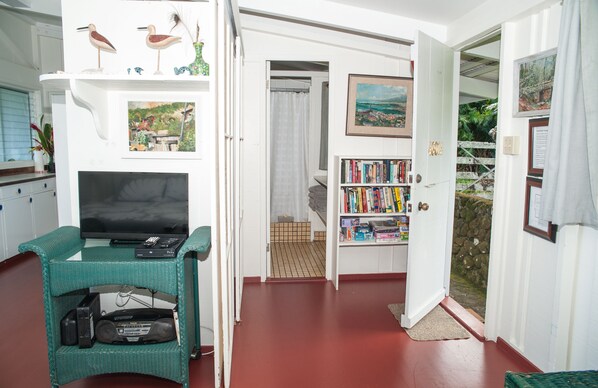 A living room with a television, bookshelf, and a door leading to a balcony.