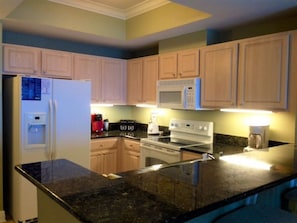 Kitchen area with a stove, microwave, coffee maker, and sink.