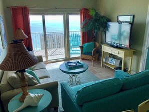 Relax in style with a comfortable sofa, TV, and ocean views through the sliding glass door.