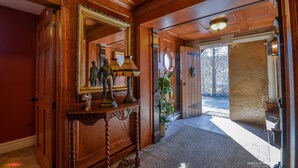 A wooden hallway with a large mirror, a lamp, and a statue on a console table. - Amazing Unique Church for rent  - St. Cecilia by the Sea (Purcells Cove)